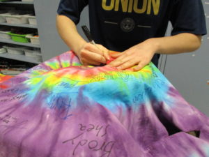 Junior Roxanna Fouladi signs the sacred multi-colored lab aide coat, leaving her mark on the chemistry department.  The SPOKE/Meagan O'Rourke