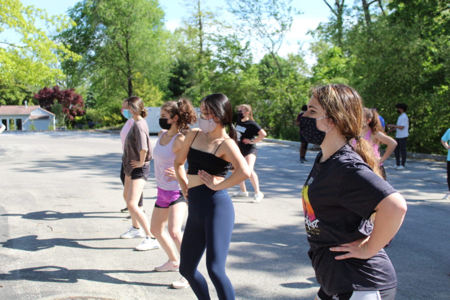 Performers in the musical learn their choreography in the school parking lot near the baseball field. The theater department moved the musical outdoors this year so they could adhere to COVID-19 guidelines and have a live audience.