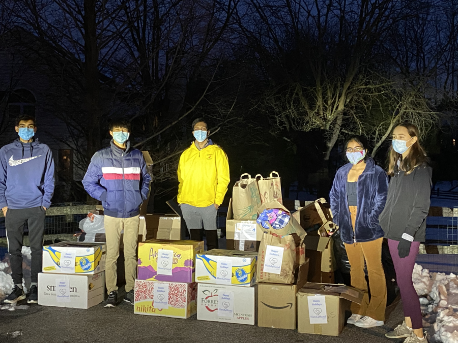 The Hand4Hand team proudly stands by a collection of food and materials from one of their drives. The donations were made by local families, neighbors and friends.