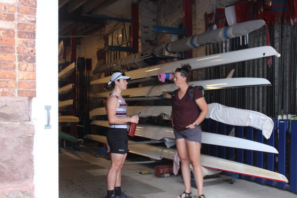 Making improvements: Head crew coach Bailey Chick converses with senior Hudson Miller as they get ready for practice at Boathouse Row in Philadelphia. She started coaching in September and has implemented new strategies and made small tweaks to the already successful crew program.