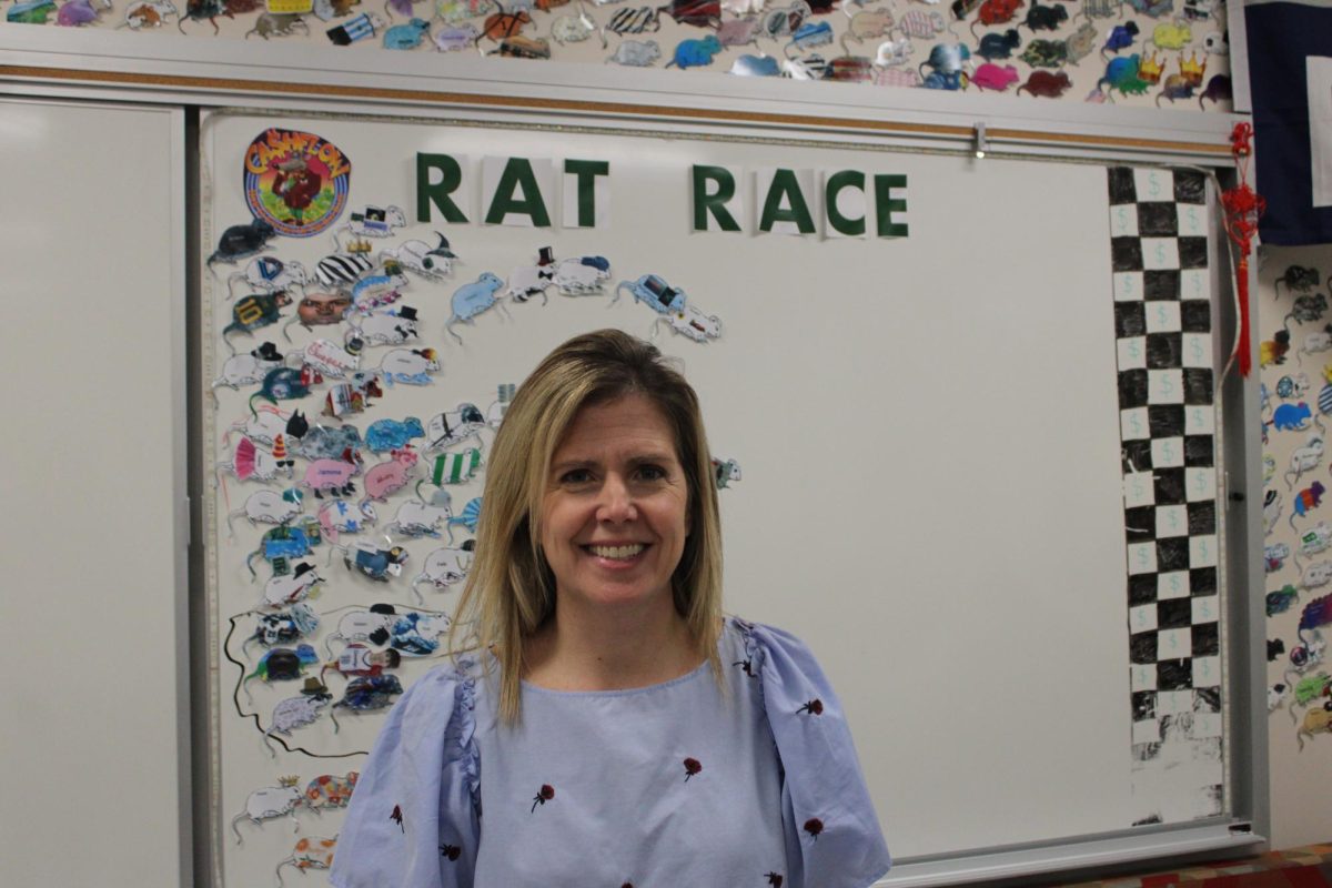 Running the rat race: Personal finance and accounting teacher Bernadette D’Emilio poses in front of the Rat Race Board, an activity in her personal finance class. D’Emilio began teaching at Conestoga in 2006 after working at Sun Valley High School.