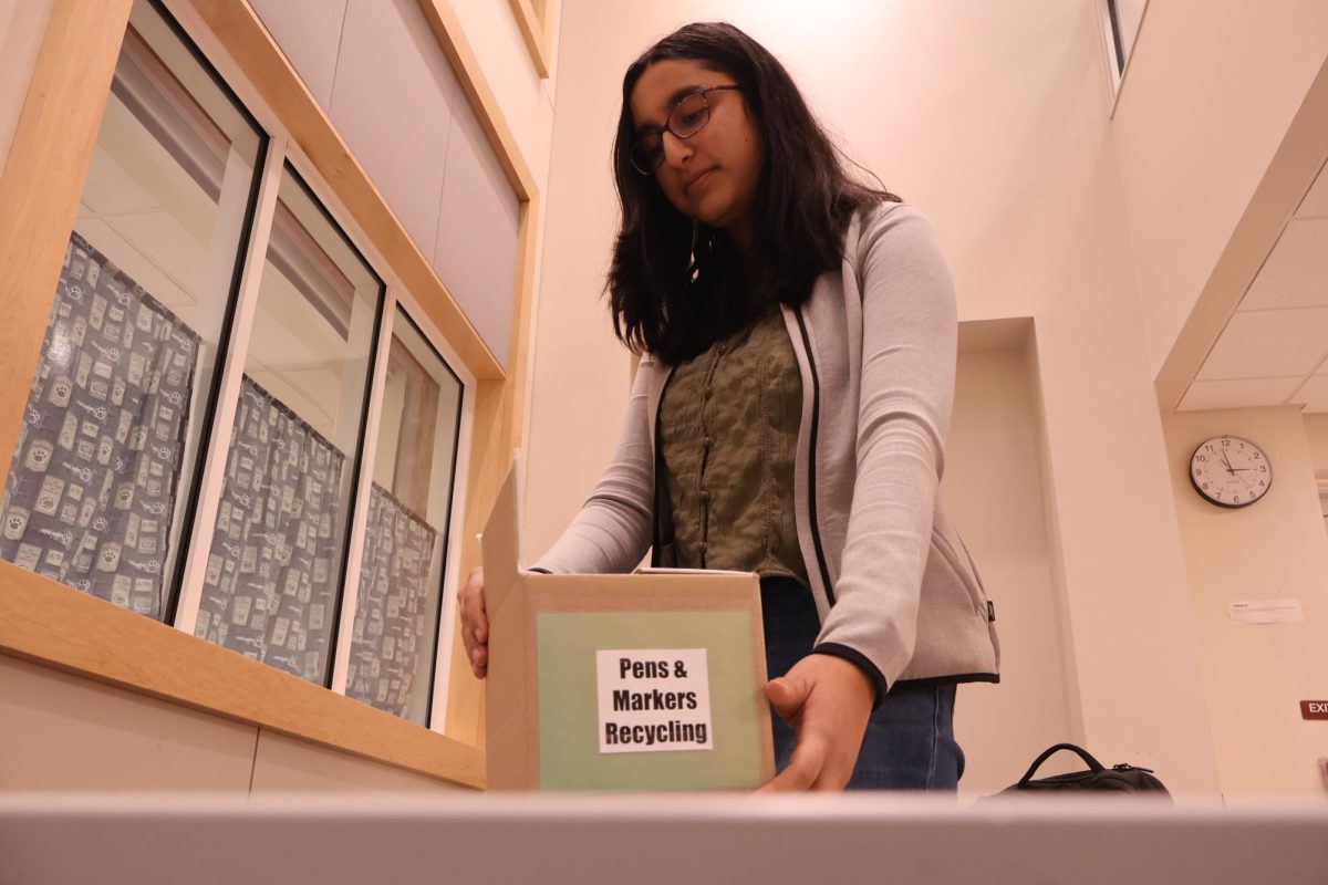 Setting sustainable standards: Senior Shriya Prakash places a collection box on a table for Conestoga staff and students to recycle pens and other writing utensils. As co-president of environmental club Greening ’Stoga Task Force, she helped audit elementary schools.