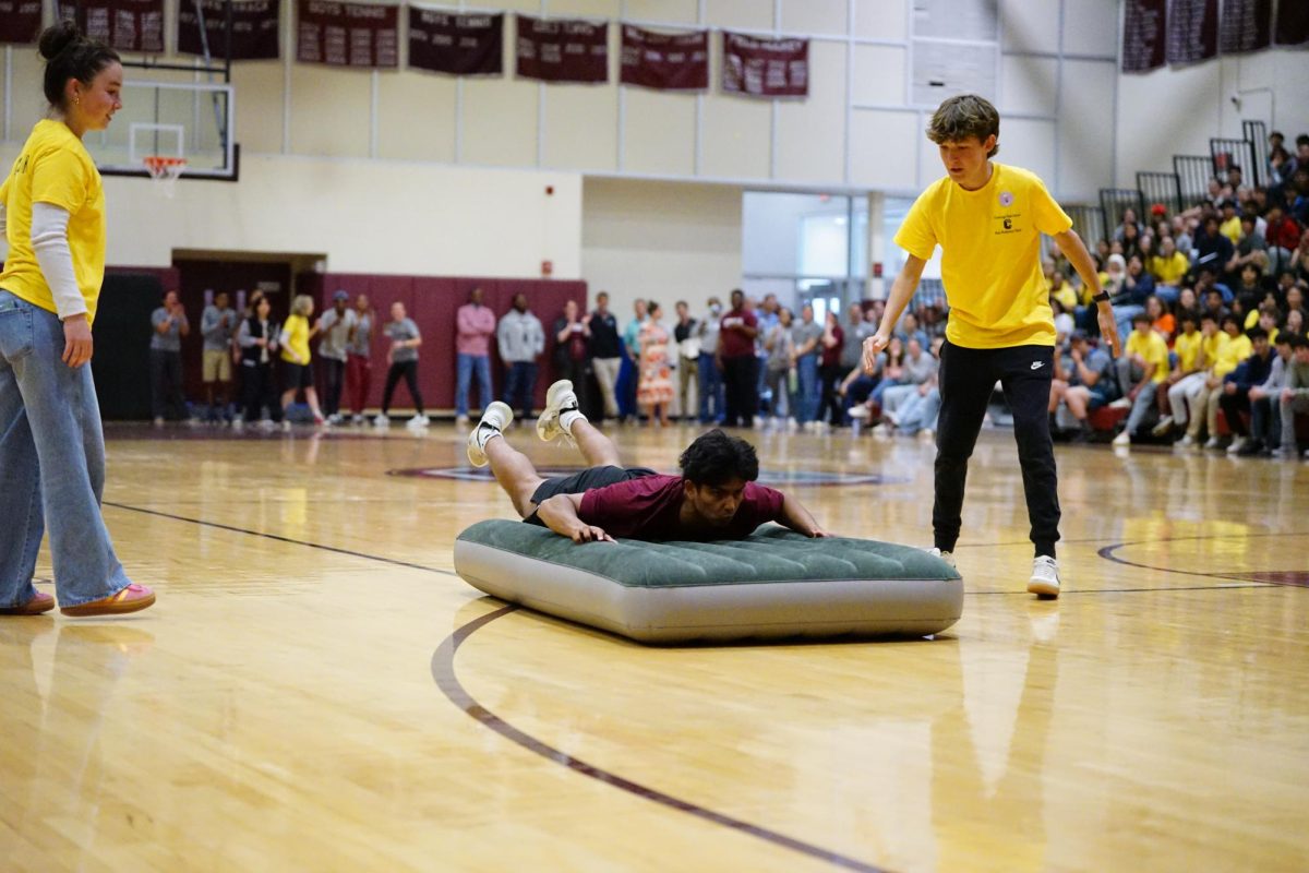 Friendly competition: Junior Krtin Ashokkumar slides across the gym floor during the air matress relay race. Peer Mediation hosted Unity Fair on May 23 with the goal to reduce stress and bring the school together, hosting fun activities throughout the day.
