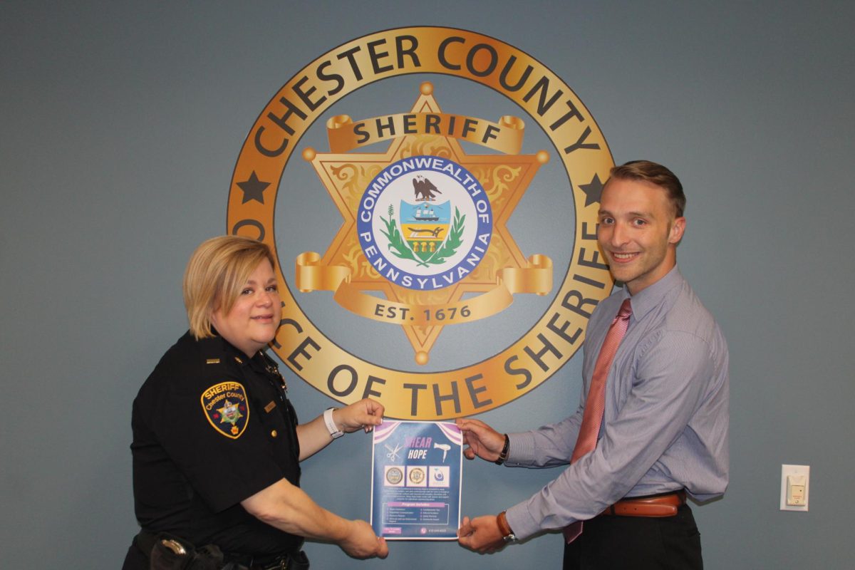 Combatting domestic violence: The Chester County Sheriff’s Office’s Lieutenant Janis Pickell (left) and command staff liaison Noah Stribrny (right) hold a flyer for Shear Hope. They partnered with two other agencies to launch the Shear Hope program.