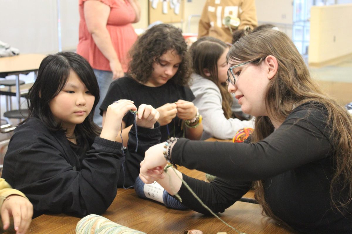 Crocheting classes: Junior and Girl Scout Kate Orr helps a student learn the single chain pattern in her crocheting class for children. Orr assembled a team of five assistants to teach Girl Scout troops across the county.