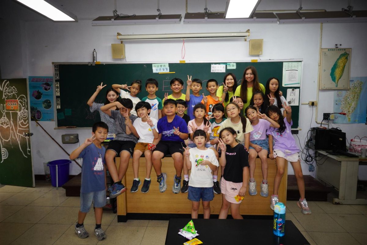 Love of language: Senior Joanna Harris (back row, second from right) poses with students in their school in the Taichung area of Taiwan. Harris participated in a month-long program where she taught the English language to kids who speak Mandarin while living with a host family.