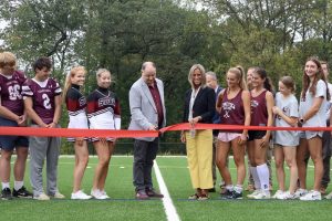 First of the fields: Student athletes join district officials to open the first field of the Athletic Fields Project. The ribbon-cutting ceremony occurred on Sept. 24 and the field hockey team practiced on the turf after.