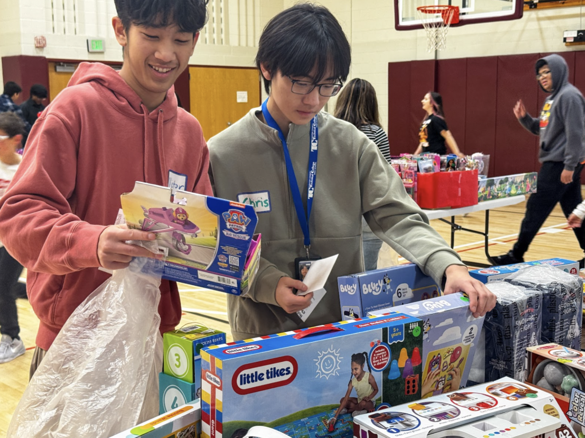 Holiday helpers: Seniors and Paoli Allied Health students Victor Pan (left) and Chris Song (right) select gifts using recommendation vouchers during the Holiday Hope Chest event at TCHS Pickering. Students in the Paoli Allied Health program raised money to purchase toys and volunteered to support families in need during the holiday season.