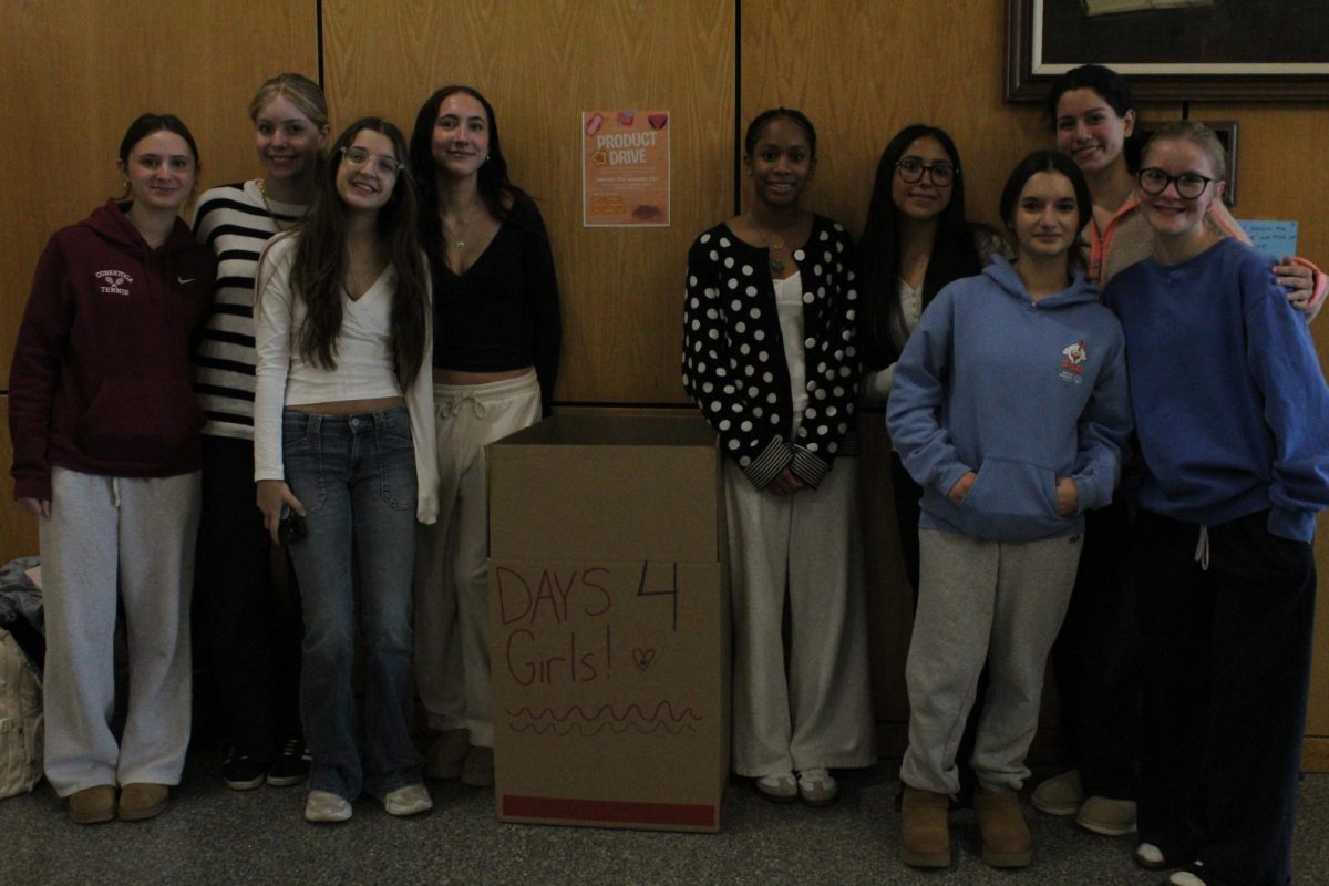 Turning awareness into action: Days for Girls board members stand in front of a collection box in support of the club’s school-wide menstrual product drive. The students launched the drive to raise awareness for period poverty and collect menstrual products for hygiene kits that will be distributed globally.