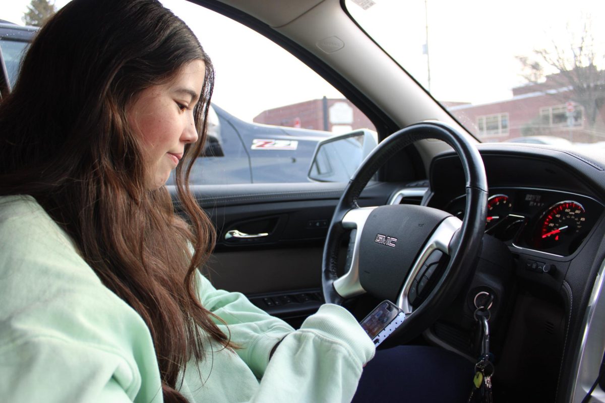 Scrolling while parked: Sophomore Sami Middaugh uses her phone while in the driver’s seat. The Paul Miller’s Law began enforcing warnings for drivers using hand-held devices on June 5, 2025. It will implement a $50 fine starting in June 2026.