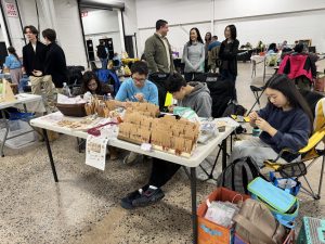 Handmade help: Sophomores Yosuke Imamura (left) and Yubo Jin (middle) and Japanese Language School of Philadelphia student Suzu Noda (right) fold origami at a table to sell for Imamura’s nonprofit, the PurrfectHome Project, at a Kids Market event in February. They have been working together to raise money for cats and dogs in need.